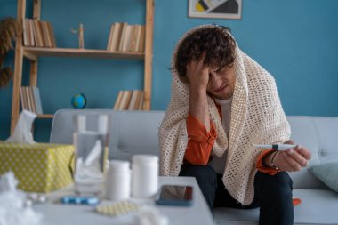 Kanepede otururken battaniyeye sarılmış, ateşi ölçen hasta bir adam. Evde otururken termometreye bakan eli başının üstünde gergin genç bir Arap. Boşluğu kopyala