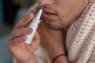 Hasta adamın evde hasta yatarken burun spreyi kullanmasına yakın çekim. Rhinitis, ilaç ve sağlık hizmeti kavramı
