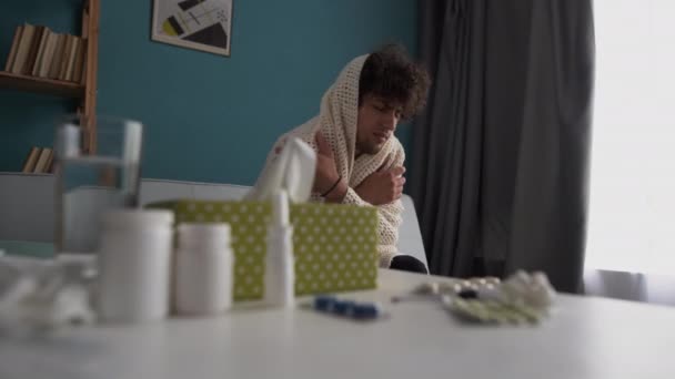 寒さと人々の概念 前景に丸薬でソファに座っているアラビア人の男はインフルエンザと頭痛に苦しんでいます スペースのコピー — ストック動画