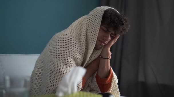 年轻的阿拉伯病人坐在沙发上 裹着温暖的毛毯 却饱受发热之苦 流感与感冒治疗概念 — 图库视频影像