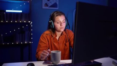 Genç bayan oyuncu, gece bir fincan kahveyle karanlık bir odada otururken ve kişisel bilgisayarında video oyunları oynarken kulaklık takıyor. Oyuncu kahve içer ve akarsu oyunu oynar. Boşluğu kopyala