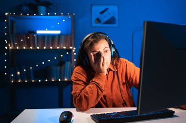 Kadın oyuncu, evdeki neon ışıkta kişisel bilgisayarda çevrimiçi video oyununda oynarken bunalıma giriyor. Oyuncu yaşam tarzı, E-Sport online oyun teknolojisi konsepti. Boşluğu kopyala