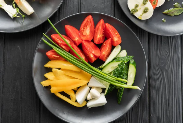 健康的蔬菜沙拉 新鲜西红柿 洋葱和大蒜放在黑盘上 节食菜单 顶部视图 复制空间 — 图库照片