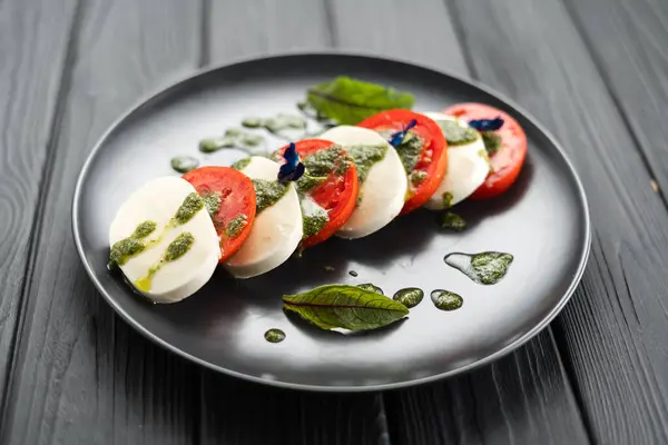 意大利卷心菜沙拉配西红柿 莫扎拉芝士 橄榄油 用黑色的木料背景放在黑色盘子上食用 意大利食品概念 — 图库照片