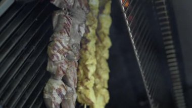 Izgarada ızgara biftek, domuz eti ve tavuk kebabı, yakın plan. Barbekü şişleri yanan ızgarada et kebabı yapar. Dikey video