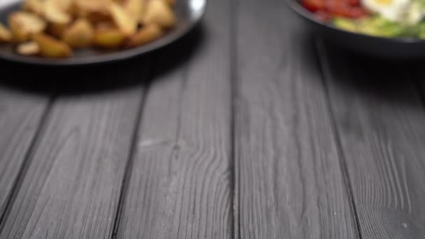 フェタチーズとギリシャのサラダ オリーブと日干しトマトは黒い木製のテーブルの上にプレート上で提供 — ストック動画