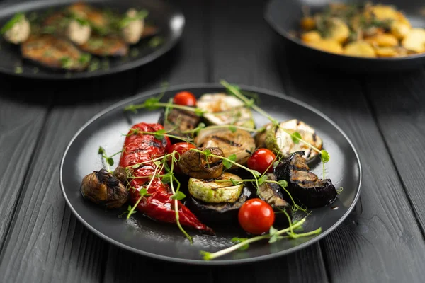 将烤蔬菜拌在盘子里 底色为黑色 木桌上的胡椒粉 胡椒粉 西红柿和微青菜 — 图库照片