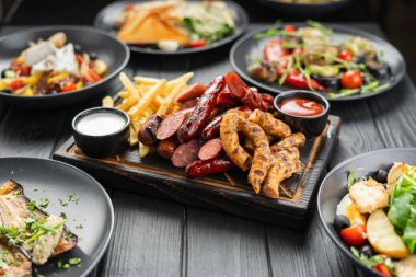 Izgarada ızgara sosis ve ahşap masada sebze salatası. Restoran ızgara menüsü. Boşluğu kopyala