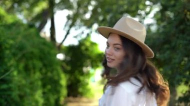 Stylish girl walking in park in spring walks along the road and smiles looking back over her shoulder. Close-up