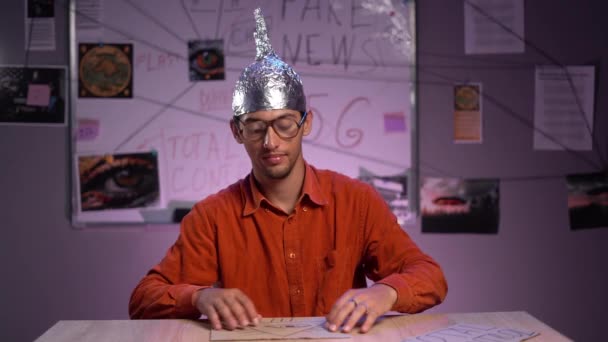 Junger Verschwörungstheoretiker Mit Aluminiummütze Sitzt Seinem Büro Und Zeigt Fake — Stockvideo