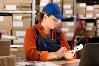 Depo çalışanı kargo teslimat listesini kontrol ediyor. Boşluğu kopyala