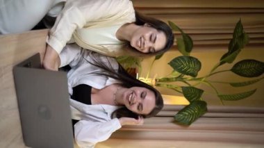 Bir kafede iki kız arkadaş laptoplarını kullanarak görüntülü görüşme yapar, internette sohbet eder ve kameraya el sallarlar. Dikey video