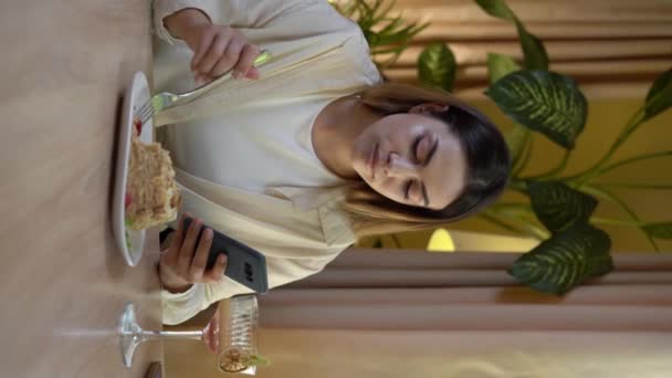 年轻女人在餐馆或咖啡店吃蛋糕 用智能手机发短信 垂直录像 — 图库视频影像