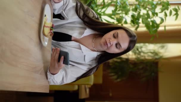 Молодая Женщина Ест Торт Ресторане Кафе Пишет Смс Смартфоне Вертикальное — стоковое видео