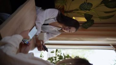 Her zaman bağlı, kafede akıllı telefonlarına bakan iki genç kadın. Sosyal ağ ve internet bağımlılığı kavramı. Dikey video