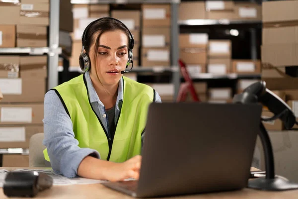 Portrait of a warehouse staff listening and talking to a customer using a headset while working in a distribution warehouse. female call center or support operator working in online stores.