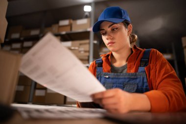Teslimat paketleri için barkodları tutan kadın. Depoya teslim edilmeden önce karton paketlerin barkodlarını hazırlayan bir işçi. Fabrika deposunda çalışan bir kadın. Boşluğu kopyala