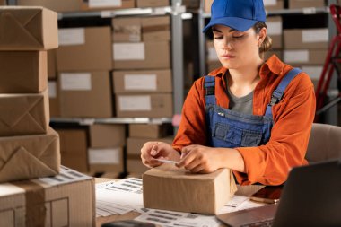 Çevrimiçi mağaza sahibi paket kutusuna barkod etiketi yapıştırıyor. İş kadını bir depoya nakliye siparişi hazırlıyor. Küçük bir e-ticaret şirketi işleten kadın girişimciler. Boşluğu kopyala