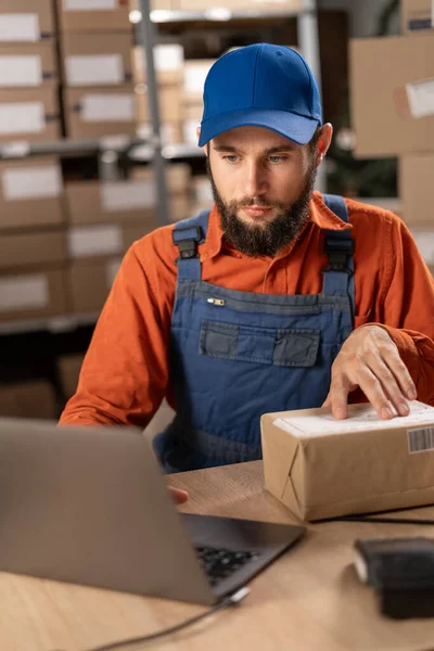 Depo Yöneticisi Dizüstü Bilgisayarı Kullanarak Bir Paketin Sipariş Numarasını Kontrol — Stok fotoğraf