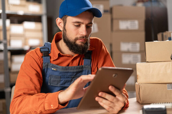 Portrait of a professional male worker uses digital tablet with inventory checking software in the retail warehouse. Delivery, Distribution Center. Copy space