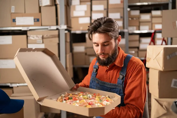 在仓库吃午饭时 穿着制服的体力劳动者手里拿着美味的披萨 复制空间 — 图库照片