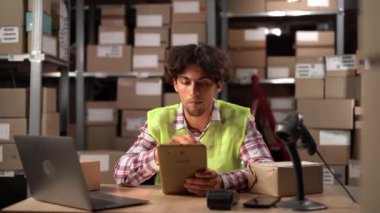 Genç Arap depo çalışanı dizüstü bilgisayar ve dijital tablet kullanıyor. Boşluğu kopyala