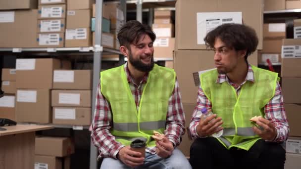 倉庫でコーヒーブレイクやランチ中にユニフォームの労働者が互いに話し合っている コピースペース — ストック動画