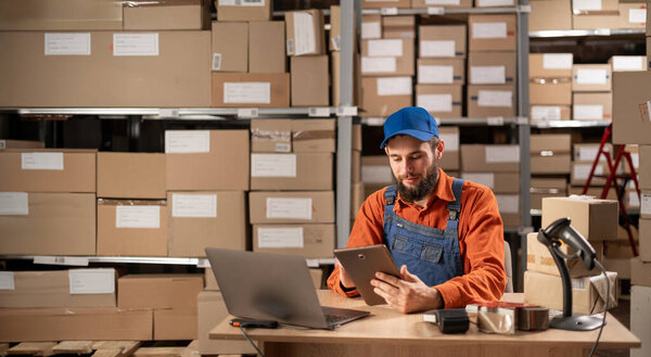 Portrait of a professional male worker uses digital tablet with inventory checking software in the retail warehouse. Delivery, Distribution Center. Copy space