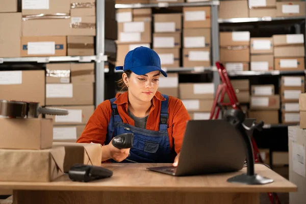 Delivery business. A young woman in a warehouse working with a laptop uses a barcode scanner enters data into the program. Copy space