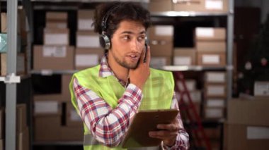 Lojistik dağıtım deposunda dijital tablet kullanan genç bir Arap işçi. Boşluğu kopyala
