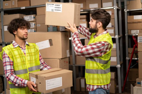 Two mixed race warehouse workers preparing a shipment in a large warehouse. Logistics employees working in warehouse in a large distribution center. Copy space