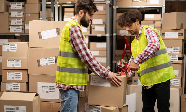 Dois Trabalhadores Armazém Selando Caixas Papelão Para Transporte Grande Armazém — Fotografia de Stock