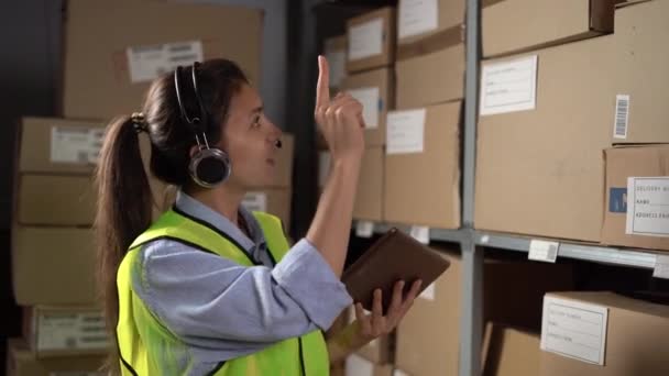 Pracownica Nosząca Słuchawki Przy Użyciu Tabletu Cyfrowego Pracująca Magazynie Logistycznym — Wideo stockowe