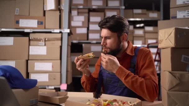 倉庫の労働者は 職場に座っている間 休憩中に美味しいピザを食べる コピースペース — ストック動画