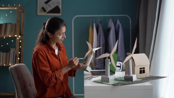 ホームオフィスの3D風力タービンモデルで働く女性デザイナー 再生可能エネルギープロジェクトに取り組む革新的なビジネスウーマン コピースペース — ストック動画
