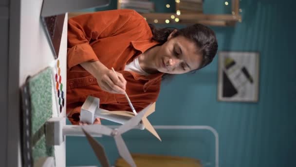 千年妇女在家里为未来的风车模型工作 复制空间 垂直录像 — 图库视频影像