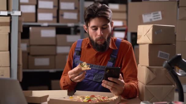 Склад Чоловік Працівник Або Менеджер Їсть Піцу Прокручує Свій Телефон — стокове відео