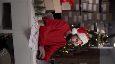 Delikanlı bir depoda çalışıyor. Bilgisayarlı e-ticaret ve küçük işletme konseptini kullanarak internetten Noel siparişi alıyor. Dikey video