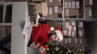 Noel arifesinde perakende mağazalarında çalışan bir çalışan. Küçük işletme sahipleri teslimat ya da sevkiyat için paketleme ve paketleme yapıyor. Dikey video