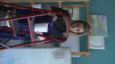 Kadın sanatçı akrilik boyaları karıştırıyor. Sanat ressamı soyut resim üzerinde çalışır, iki rengi karıştırır. İşlem halindeki ressam sanat eseri yaratıyor. Dikey video