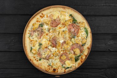 Tavuk fileto, domuz pastırması ve ahşap masada ıspanak ile pizza. Düz yatıyordu