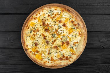 İtalyan peynirli pizzanın en iyi manzarası. Siyah ahşap arka planda peynirli pizza. Geleneksel İtalyan mutfağı. Düz yatıyordu