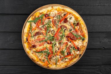 Mozarella peynirli, salamlı, mantarlı, domates soslu, zeytinli, kırmızı biberli ve ahşap zemin üzerinde parmesanlı taze pişmiş pizza. Boşluğu kopyala