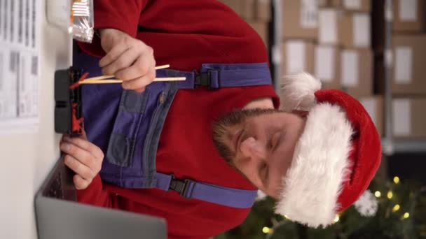 クリスマスのお正月のための寿司 倉庫労働者のための冬の休日の食糧配達 サンタが寿司ロールを食べるのは 残業中の箸で バーティカルビデオ — ストック動画