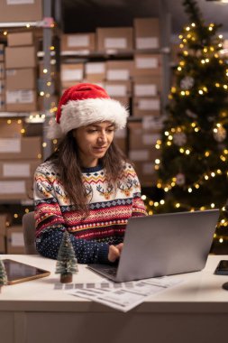 Depo Noel arifesinde postanede hızlı teslimat hazırlıyor. Noel Baba şapkalı kadın postacı.