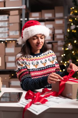 Mutlu Noeller nakliye konsepti. Noel Baba hediye paketini kırmızı kurdeleyle paketliyor. Posta teslimat paketini hazırlıyor. Boşluğu kopyala