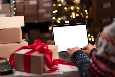 Kadın satıcı, internet mağazası Noel Baba şapkası takan küçük işletme sahibi, beyaz laptop ekranında online mağaza teslimat siparişini kontrol ediyor. E-ticaret, Noel indirimi konsepti.