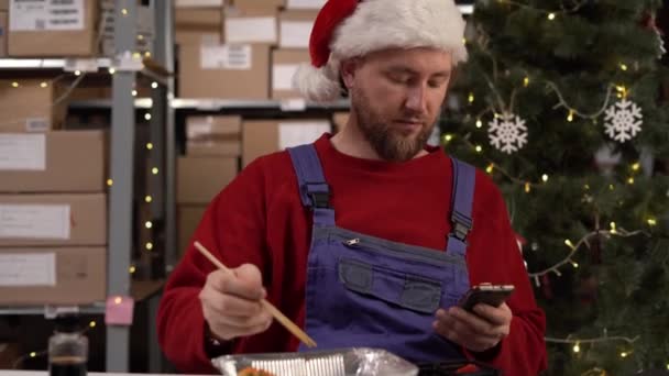 一个留着胡子的男人在仓库里用筷子吃寿司的时候用的是手机 复制空间 — 图库视频影像