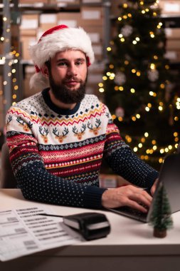 Yoğun modern depoda dizüstü bilgisayarla çalışan erkek işçilerin portresi, Noel indirimi konsepti. Yakın plan.