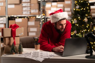 Erkek çevrimiçi mağaza küçük işletme sahibi girişimci siparişleri kontrol etmek için dizüstü bilgisayar hazırlama teslimat paketini masaya koyuyor. Noel indirimi. Nakliye konsepti. Boşluğu kopyala